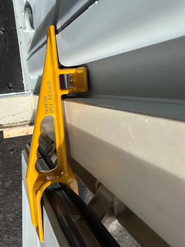 The brace's foot slotted behind the container's lashing bar