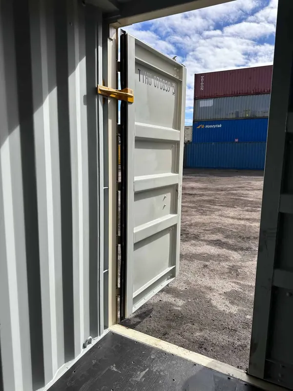 A container door held open by the brace at the hinge side, yard behind